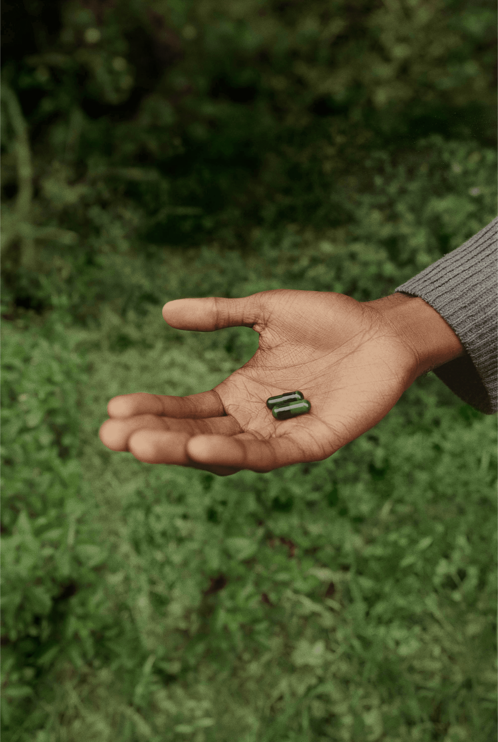 Open hand holding green capsules outside
