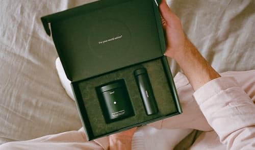 Person holding a green box with two black items inside