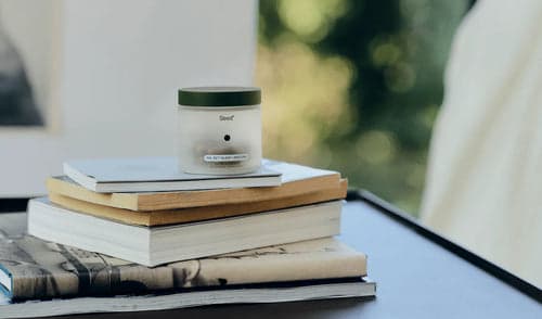 Candle on a stack of books with a blurred natural background