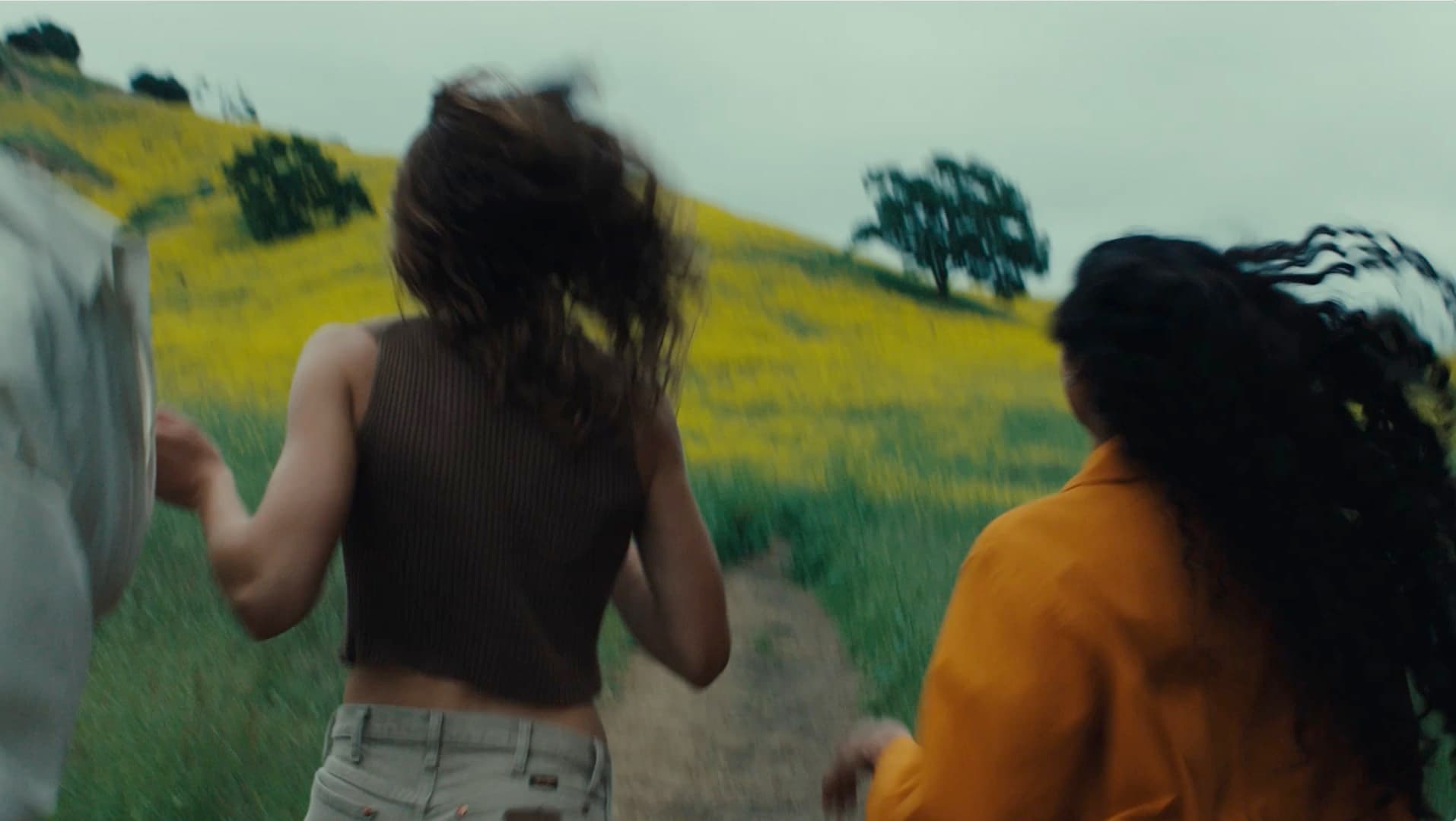 Three people running in a green field